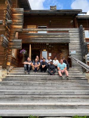 Volunteers sittin on the stairs of a log house. Photo
